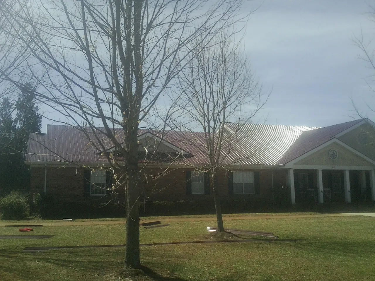 Red metal roof on a brick building seen from the front lawn in Clinton